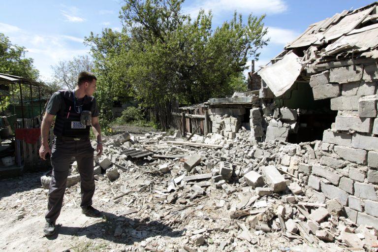 Сотрудник ОБСЕ осматривает двор жилого дома, пострадавший в результате обстрела Докучаевска в Донецкой области Сотрудник ОБСЕ осматривает двор жилого дома, пострадавший в результате обстрела Докучаевска в Донецкой области