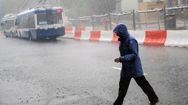 Прохожий во время ливня на одной из улиц Москвы. Архивное фото