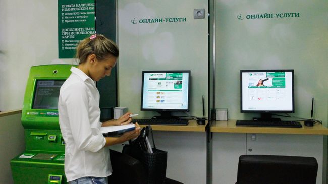 Сотрудница дополнительного офиса Сбербанка в зале обслуживания. Архивное фото Сотрудница дополнительного офиса Сбербанка в зале обслуживания. Архивное фото