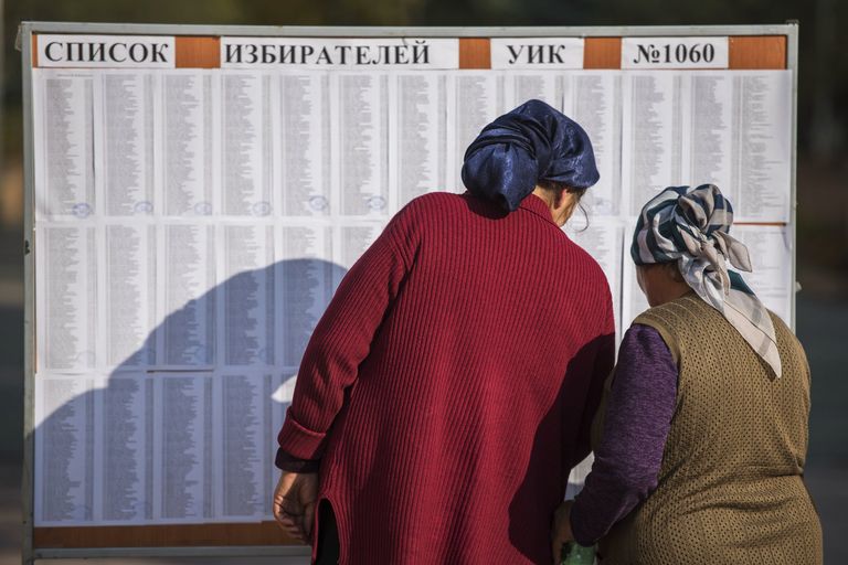 Женщины ищут свои фамилии в списке избирателей на избирательном участке в Бишкеке, чтобы проголосовать на выборах президента Киргизии. 15 октября 2017
