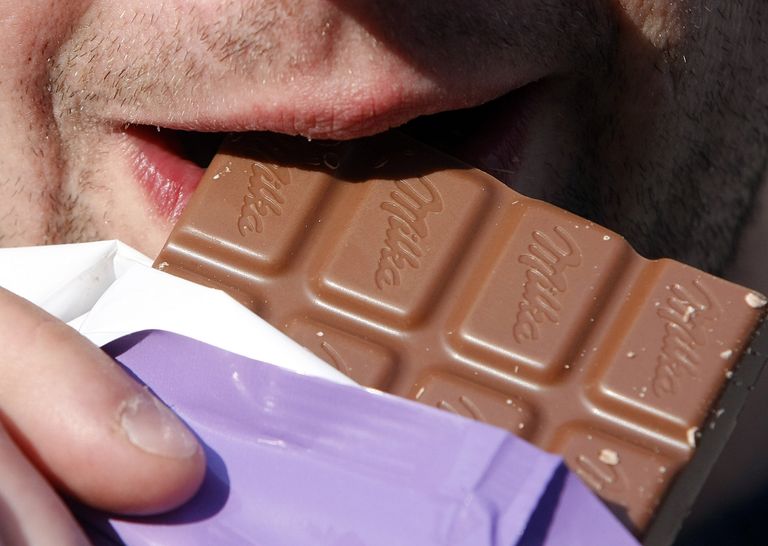 Мужчина ест шоколад Milka Мужчина ест шоколад Milka