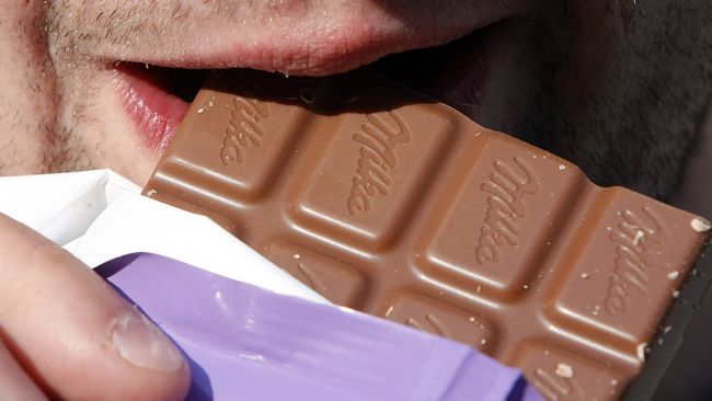 Мужчина ест шоколад Milka 