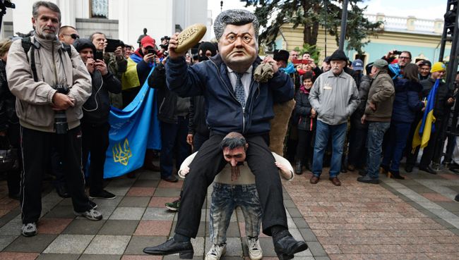 Ряженый в костюме президента Украины Петра Порошенко, который сидит на плечах у украинского казака, во время вече у здания Верховной рады в Киеве Ряженый в костюме президента Украины Петра Порошенко, который сидит на плечах у украинского казака, во время вече у здания Верховной рады в Киеве