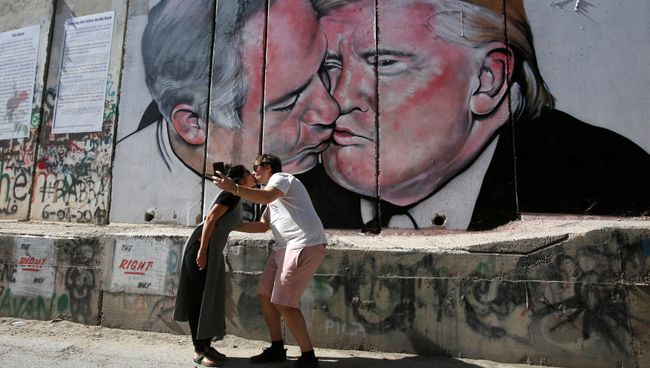 Граффити с поцелем Дональда Трампа и Биньямина Нетаньяху на стене между Израилем и Палестиной в Вифлееме, Израиль Граффити с поцелем Дональда Трампа и Биньямина Нетаньяху на стене между Израилем и Палестиной в Вифлееме, Израиль