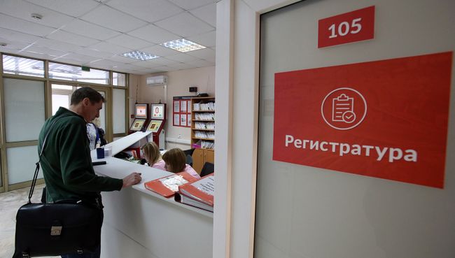 Посетитель у регистрационного стола в поликлинике. Архивное фото