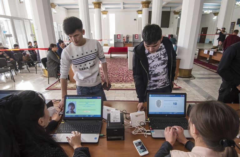 Избиратели проходят процедуру подтверждения личности с помощью сканирования отпечатка пальца на избирательном участке в Бишкеке, перед тем как проголосовать на выборах президента Киргизии