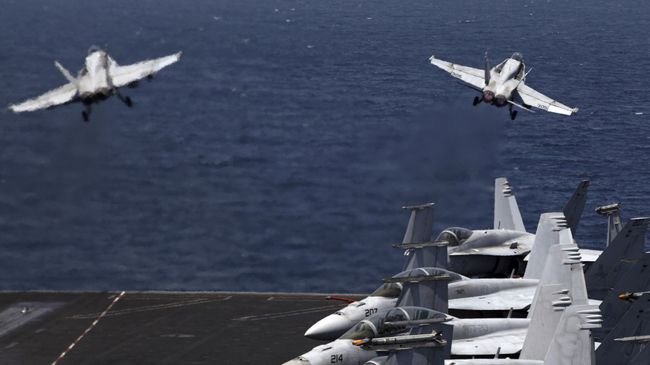 Истребители США F / A-18 вылетают с летной палубы авианосца. Архивное фото Истребители США F / A-18 вылетают с летной палубы авианосца. Архивное фото