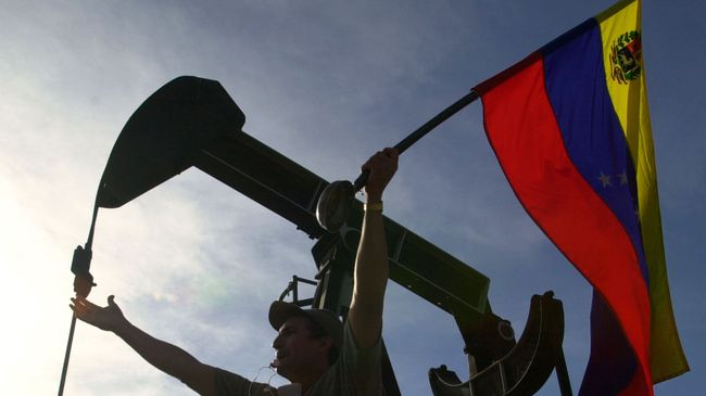 Мужчина с флагом Венесуэлы перед зданием компании PDVSA в Каракасе Мужчина с флагом Венесуэлы перед зданием компании PDVSA в Каракасе