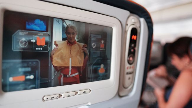 Демонстрация действий при аварии на экране кресла в салоне самолета авиакомпании. Архивное фото