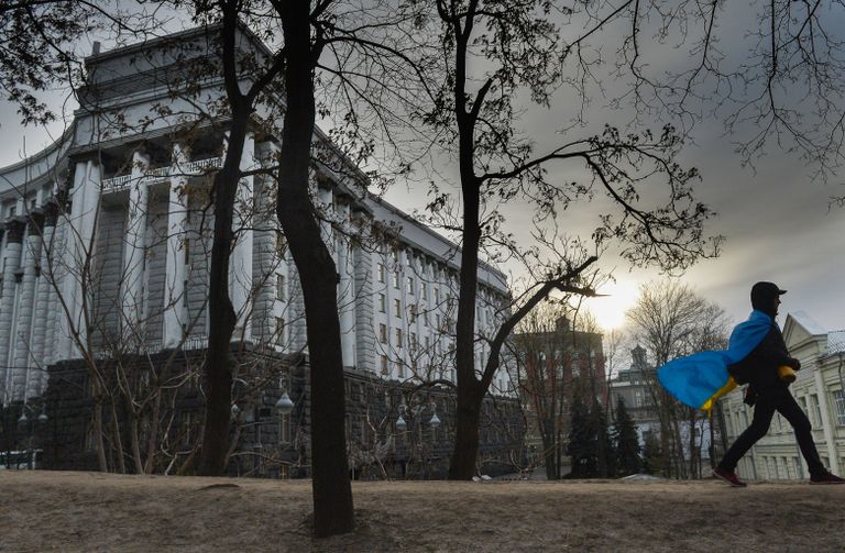 Мужчина с флагом Украины у здания правительства в Киеве, Украина