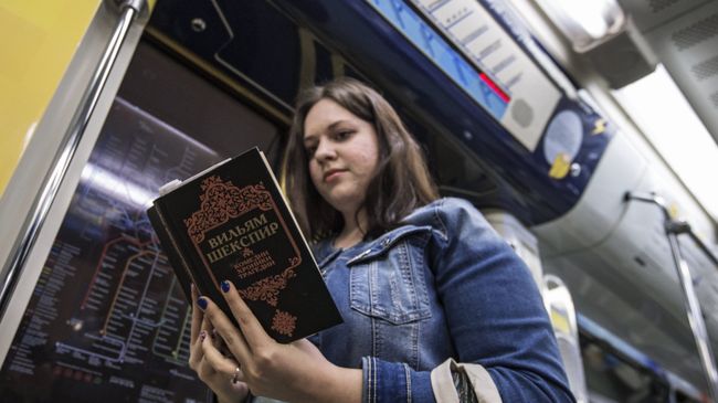 Девушка читает книгу Уильяма Шекспира в поезде московского метро