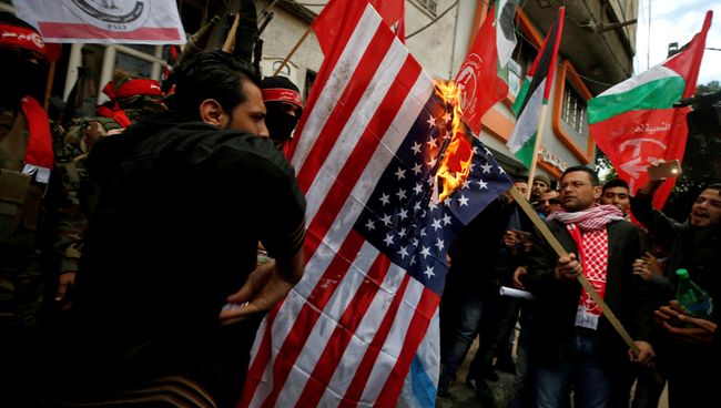 Палестинцы сжигают флаг США во время протеста против решения Трампа признать Иерусалим столицей Израиля в городе Газа. 7 декабря 2017 Палестинцы сжигают флаг США во время протеста против решения Трампа признать Иерусалим столицей Израиля в городе Газа. 7 декабря 2017