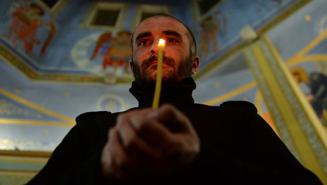 Верующий во время пасхальной службы в церкви Михаила Архангела в Грозном Верующий во время пасхальной службы в церкви Михаила Архангела в Грозном