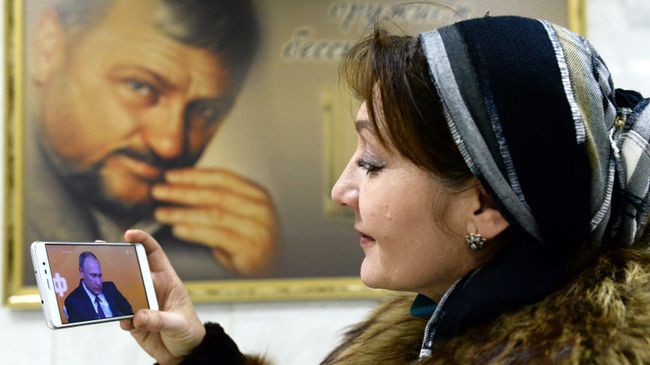 Жительница Грозного смотрит трансляцию пресс-конференции президента РФ Владимира Путина Жительница Грозного смотрит трансляцию пресс-конференции президента РФ Владимира Путина