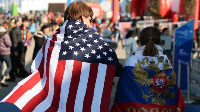 Молодые люди в национальных флагах США и России. Архивное фото Молодые люди в национальных флагах США и России. Архивное фото