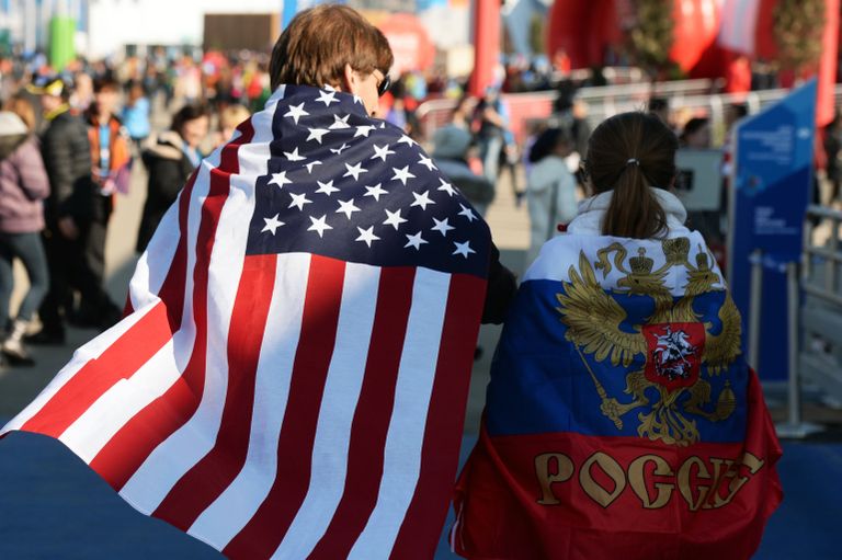 Молодые люди в национальных флагах США и России 