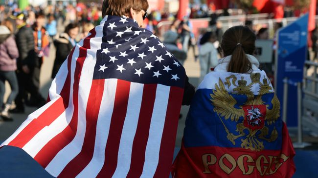 Молодые люди в национальных флагах США и России. Архивное фото Молодые люди в национальных флагах США и России. Архивное фото