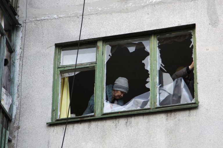 Женщина у окна жилого дома в центре города Ясиноватая, пострадавшего в результате обстрела. 21 декабря 2017 Женщина у окна жилого дома в центре города Ясиноватая, пострадавшего в результате обстрела. 21 декабря 2017