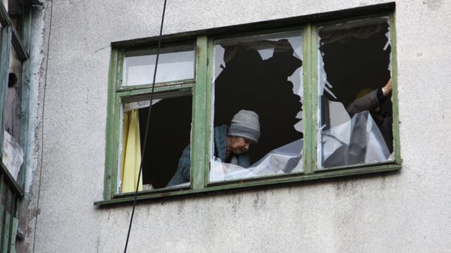 Женщина у окна жилого дома в центре города Ясиноватая, пострадавшего в результате обстрела