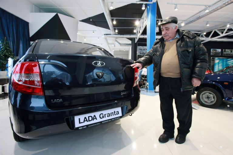 Мужчина выбирает автомобиль Лада Гранта в автосалоне