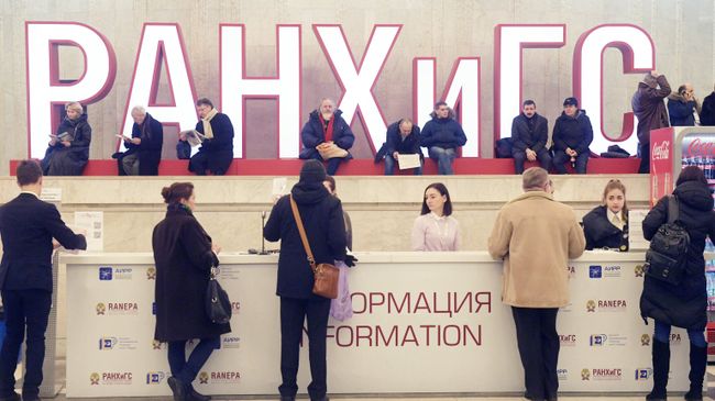Посетители у стойки информации на VIII Гайдаровском форуме Россия и мир: выбор приоритетов в Москве