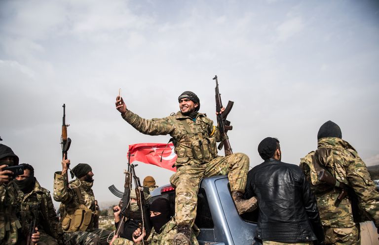 Боец сирийской оппозиции фоторафирует колонну турецких солдат около сирийской границы в Хассе, провинция Хатай. 22 января 2018 