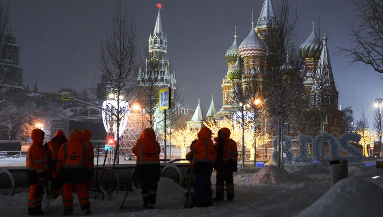 Сотрудники коммунальных служб убирают снег на улице в Москве Сотрудники коммунальных служб убирают снег на улице в Москве