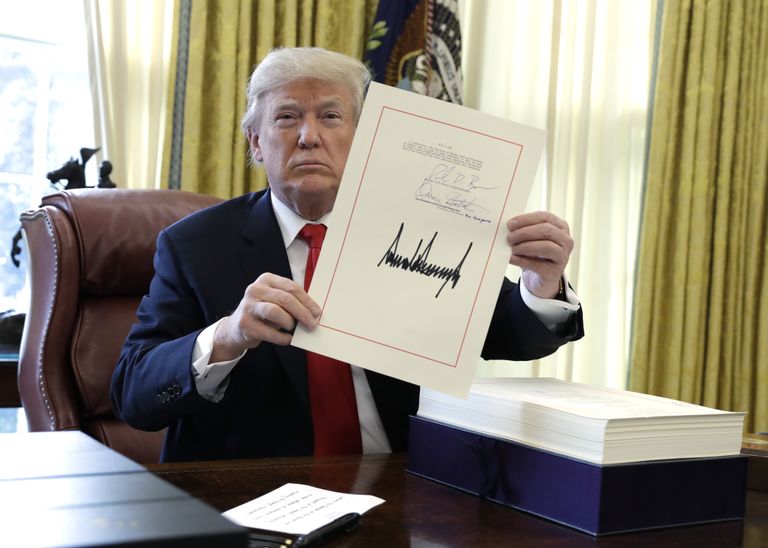 Президент США Дональд Трамп демонстрирует подписанный налоговый законопроект. 22 декабря 2017
