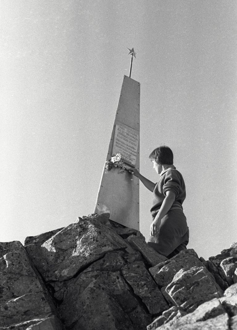 Женщина возлагает цветы к памятнику советским воинам на перевале Донгузорун