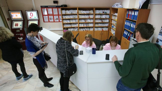 Посетители у регистрационного стола в поликлинике.  Архивное фото