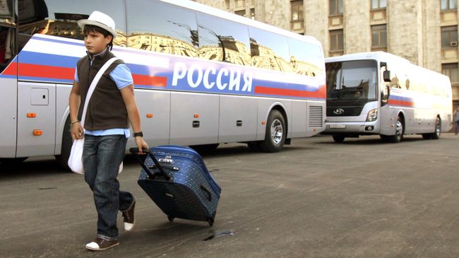 Мальчик идет возле автобуса перед отправлением в детский оздоровительный лагерь Мальчик идет возле автобуса перед отправлением в детский оздоровительный лагерь