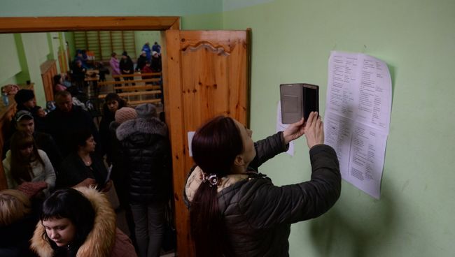 Женщина фотографирует на мобильный телефон списки пропавших без вести при пожаре в торговом центре «Зимняя вишня» в Кемерово Женщина фотографирует на мобильный телефон списки пропавших без вести при пожаре в торговом центре «Зимняя вишня» в Кемерово