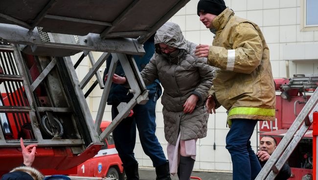 Сотрудники пожарной охраны МЧС помогают посетителям выбраться из торгового центра Зимняя вишня в Кемерово, где произошел пожар Сотрудники пожарной охраны МЧС помогают посетителям выбраться из торгового центра Зимняя вишня в Кемерово, где произошел пожар