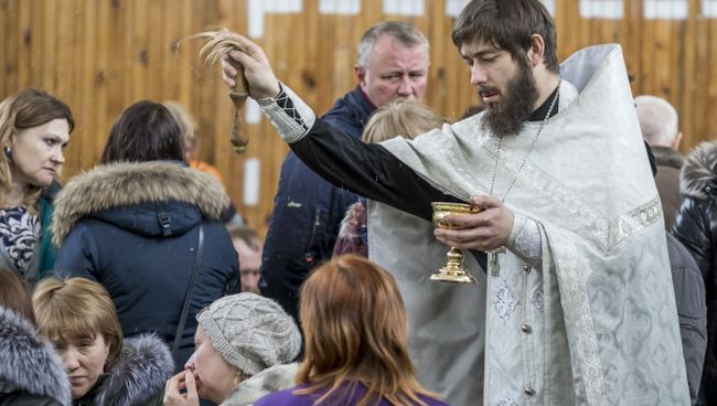 Священник проводит обряд с родственниками подстардаших при пожаре в ТЦ Зимняя вишня в Кемерово. 26 марта 2018