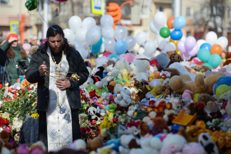 Священнослужитель у мемориала из цветов и воздушных шаров в память о жертвах пожара в торгово-развлекательном центре Зимняя вишня в Кемерово Священнослужитель у мемориала из цветов и воздушных шаров в память о жертвах пожара в торгово-развлекательном центре Зимняя вишня в Кемерово