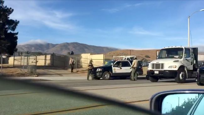 Машины полиции на дороге вблизи Highland High School в Палмдейл, где произошла стрельба. 11 мая 2018 Машины полиции на дороге вблизи Highland High School в Палмдейл, где произошла стрельба. 11 мая 2018