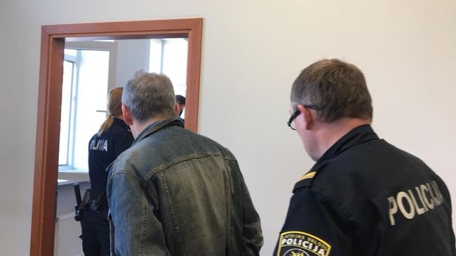 Сотрудник полиции ведет Владимира Линдермана в зал заседаний суда в Риге Сотрудник полиции ведет Владимира Линдермана в зал заседаний суда в Риге