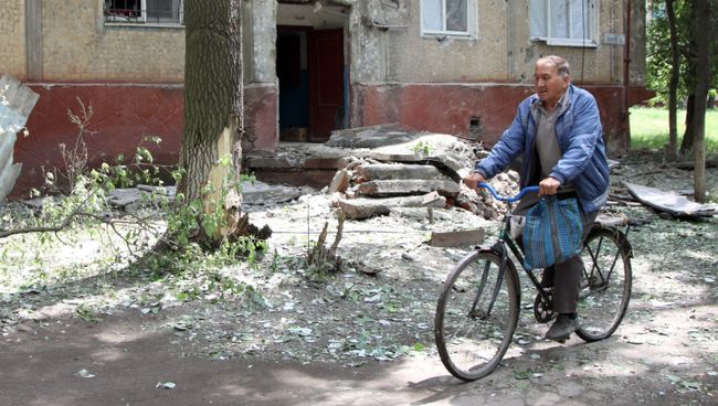 Мужчина едет на велосипеде во дворе жилого дома, пострадавшего в результате обстрела, в поселке Горловка Донецкой области. Архивное фото Мужчина едет на велосипеде во дворе жилого дома, пострадавшего в результате обстрела, в поселке Горловка Донецкой области. Архивное фото