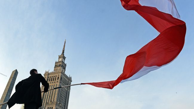 Мужчина держит польский флаг во время празднования Дня независимости в Варшаве. Архивное фото Мужчина держит польский флаг во время празднования Дня независимости в Варшаве. Архивное фото