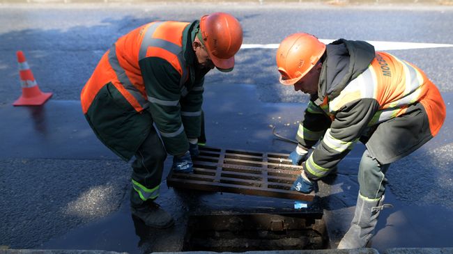 Сотрудники ГУП Мосводосток снимают решетку ливневки на Олимпийском проспекте