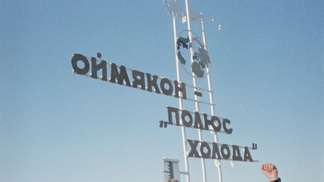 Туристы стоят у памятного знака Оймякон — полюс холода Туристы стоят у памятного знака Оймякон — полюс холода
