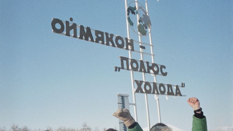 Туристы стоят у памятного знака Оймякон — полюс холода Туристы стоят у памятного знака Оймякон — полюс холода