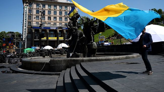 Молодой человек с украинским флагом у памятника основателям Киева на площади Независимости. Архивное фото Молодой человек с украинским флагом у памятника основателям Киева на площади Независимости. Архивное фото