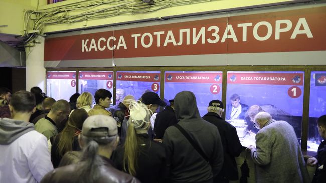 Игроки на тотализаторе делают ставки перед началом скачек на ипподроме