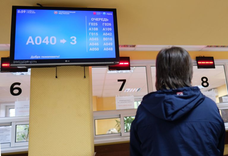 Посетитель у табло электронной очереди в отделении ГИБДД Посетитель у табло электронной очереди в отделении ГИБДД