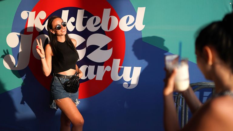 Женщина с ребенком стоит у логотипа музыкального фестиваля Koktebel Jazz Party 2018