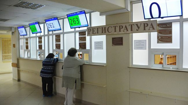 Посетители у регистратуры городской больницы. Архивное фото Посетители у регистратуры городской больницы. Архивное фото