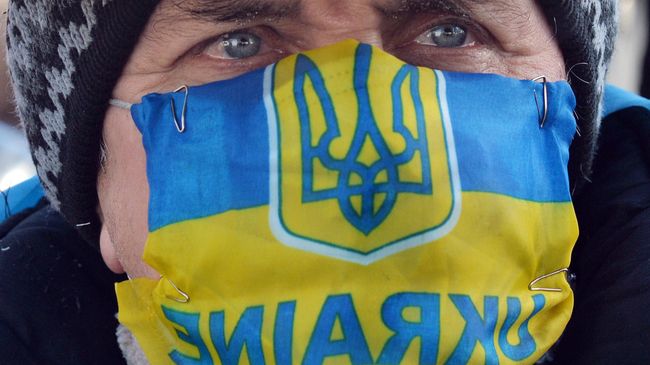Участник акции протеста в маске с изображением флага и герба Украины в Киеве. Архивное фото Участник акции протеста в маске с изображением флага и герба Украины в Киеве. Архивное фото