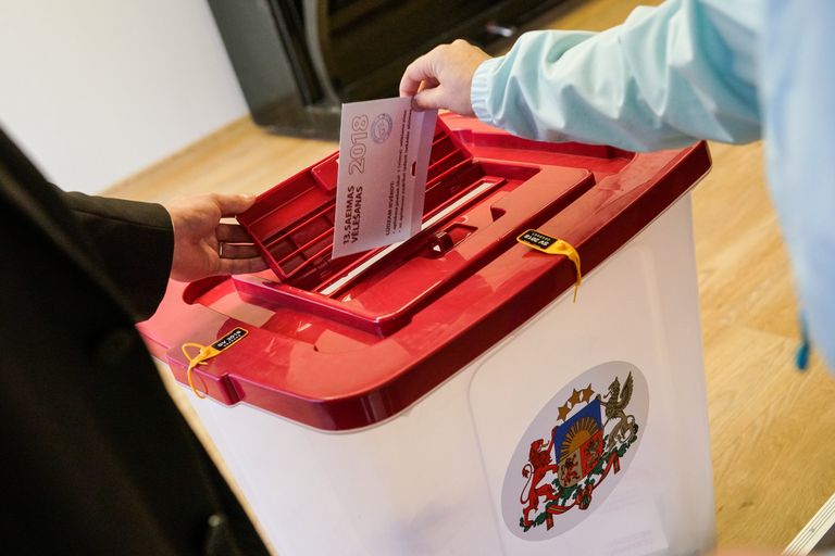 Избиратель опускает бюллетень в урну во время парламентских выборов в Латвии