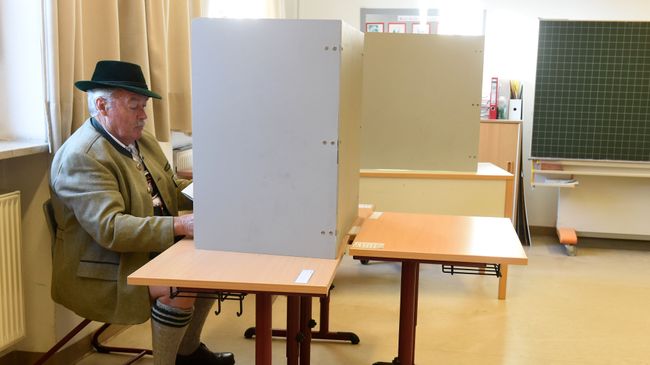 Мужчина в традиционной баварской одежде заполняет бюллетень для голосования на избирательном участке в Нойкирхене, Германия Мужчина в традиционной баварской одежде заполняет бюллетень для голосования на избирательном участке в Нойкирхене, Германия